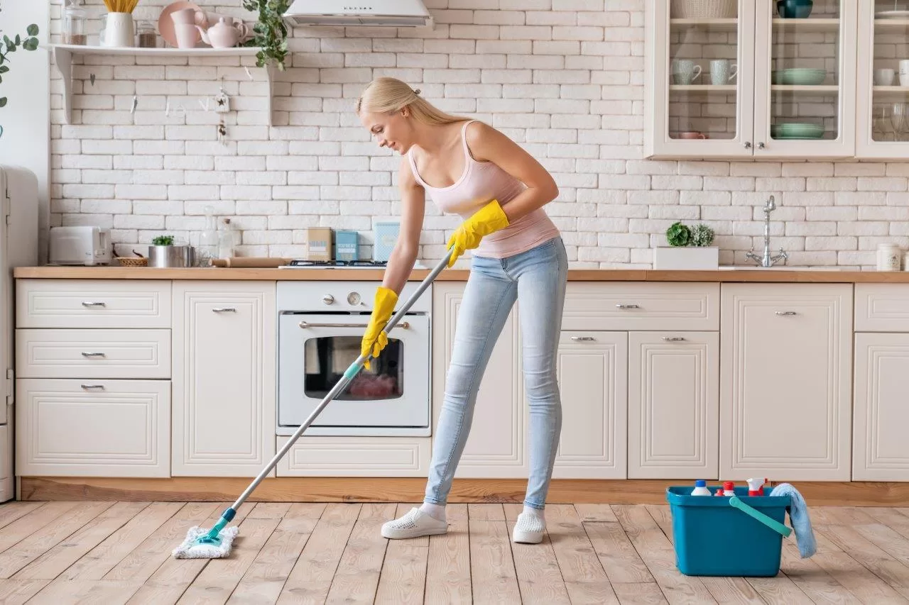 Smiling cleaning service woman with mop cleaning floor in Wilmette kitchen