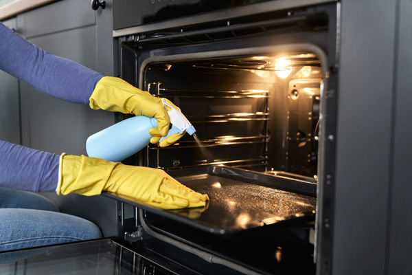 close up of woman cleaning oven at home