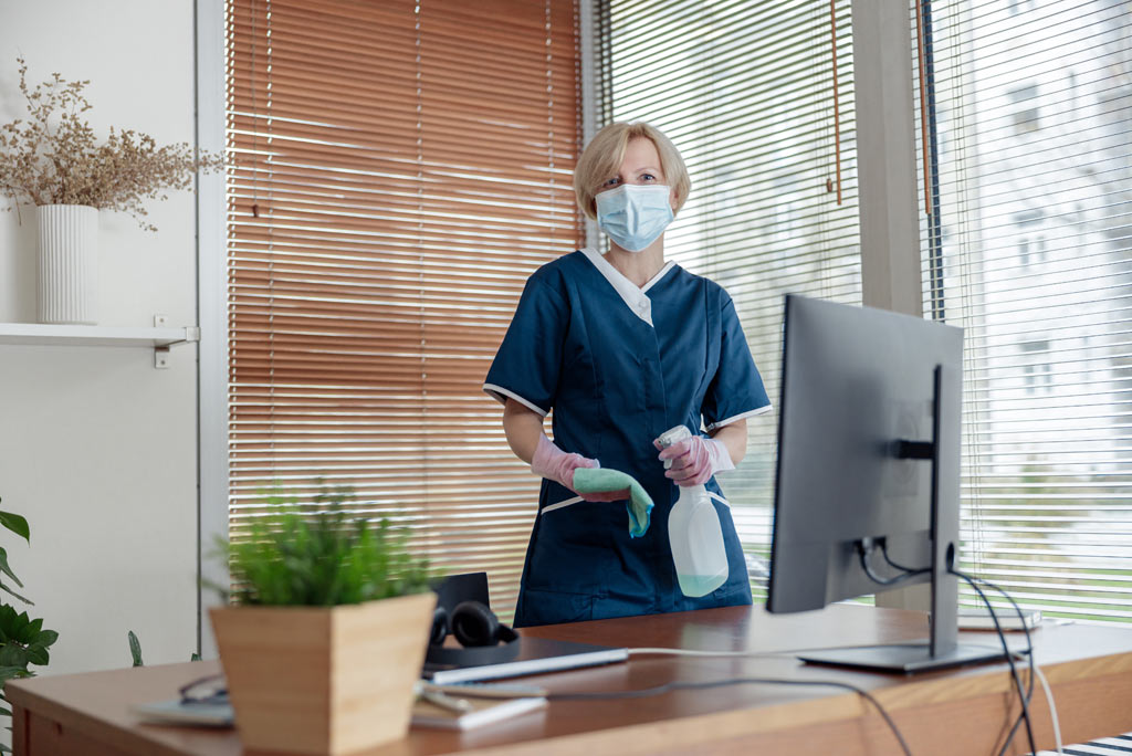 Cleaning lady om mask wiping computer