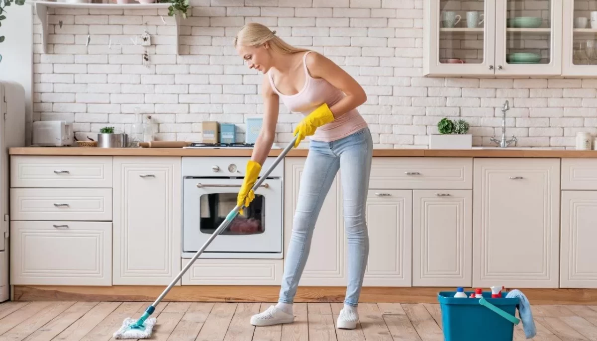 Smiling cleaning service woman with mop cleaning floor in Wilmette kitchen